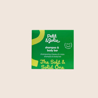 Green packaging of Petit & Jolie shampoo and body bar on a beige background